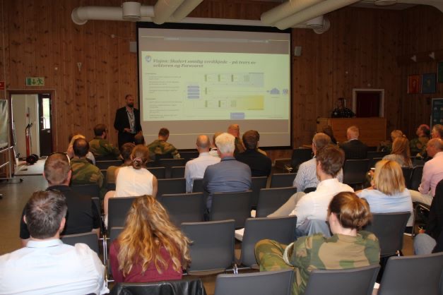 Participants in uniform and civilian clothes following a presentation in a meeting room